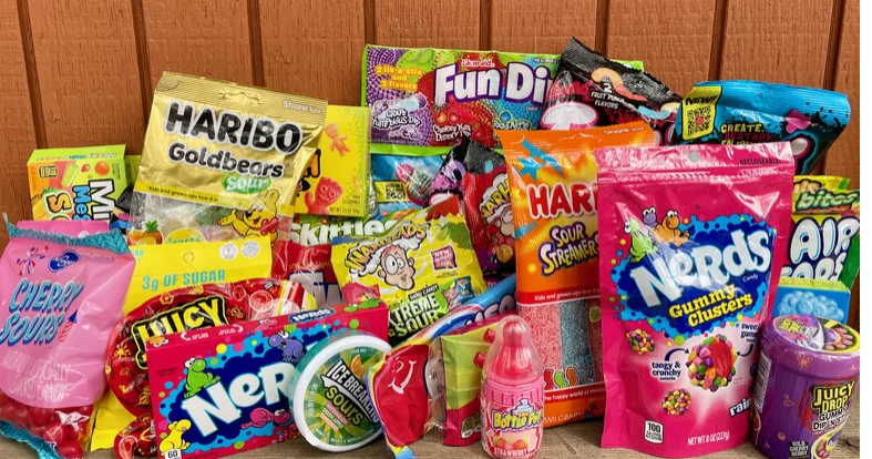 what is the most sour candy in the world A large variety of the most sour candies in the world including Nerds Gummy Clusters, Haribo Goldbears Sour, and Juicy Drop Gummies arranged on a wooden surface.