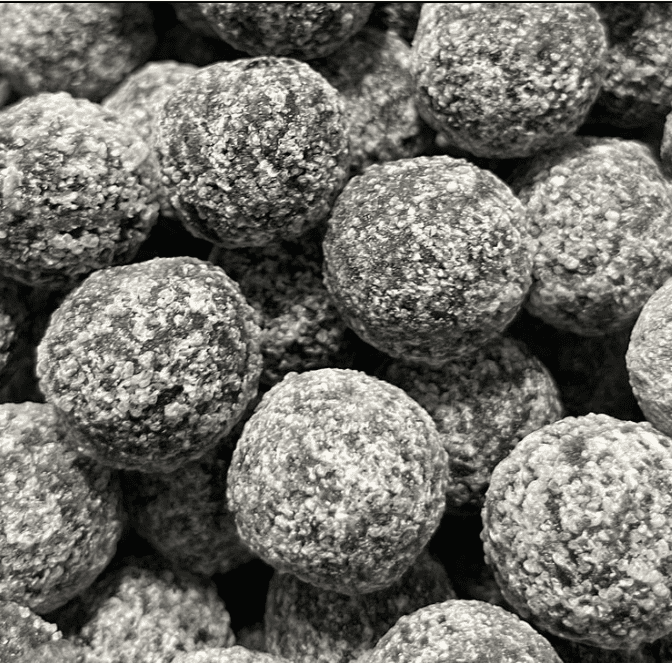 Black Death Sour Candy Challenge: 60s of Lethal Grit Close-up of black, marble-sized sour sweets heavily dusted in acidic powder for the Black Death challenge.